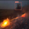 A night frame from the 2018 Holy Fire showing the FireDetect app drawing bounding boxes around active flame and smoke. The footage was YouTube video on a TV screen, the drone observed it from across the room.